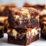Stacked chocolate chip Banana Bread Brownies with rich fudgy layers and creamy swirl texture on a white surface.
