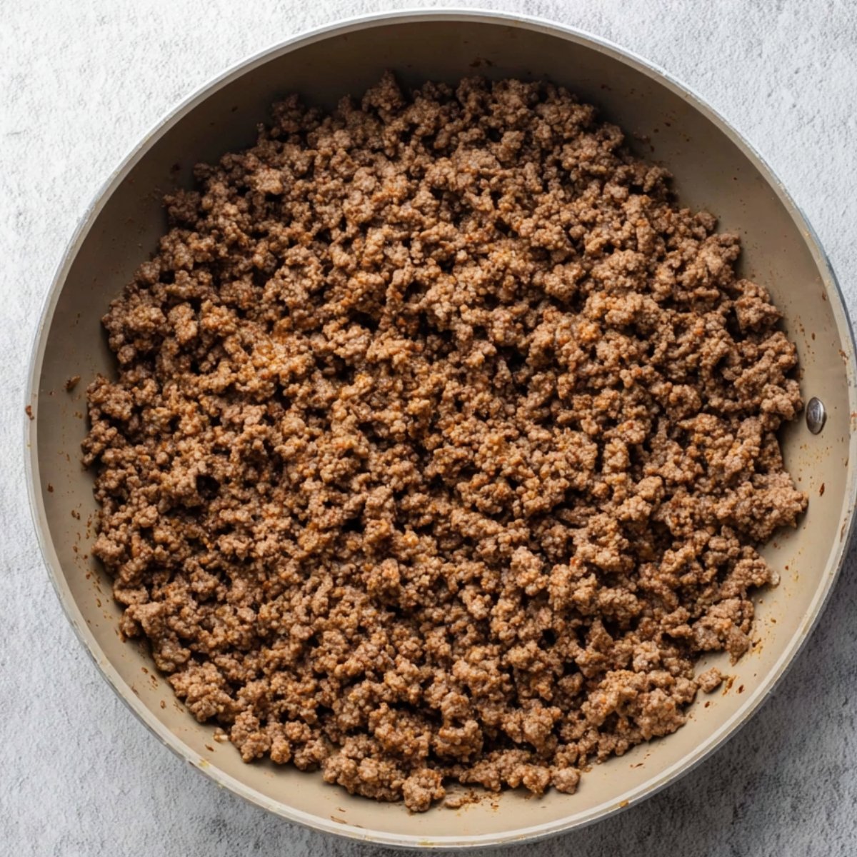 Cooked ground beef in a pan, showing a rich, browned texture, ready to be used in a variety of dishes like sloppy joe casserole or other hearty meals.