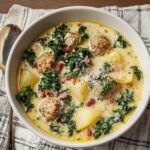 A bowl of Zuppa Toscana Soup with sausage, kale, and potatoes, garnished with Parmesan.